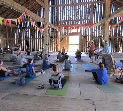 A group of farmers sit on yoga mats in a barn