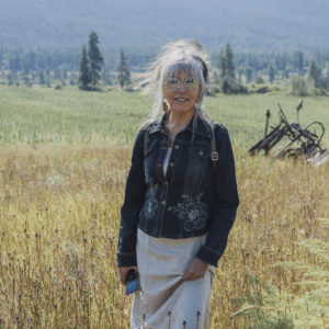 Photo of Dawn Morrison, she's wearing sunglasses and a jeans jacket, with a green field behind her