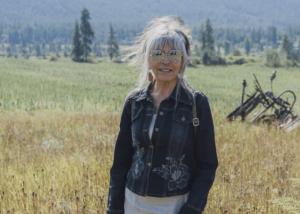 Photo of Dawn Morrison, she's wearing sunglasses and a jeans jacket, with a green field behind her