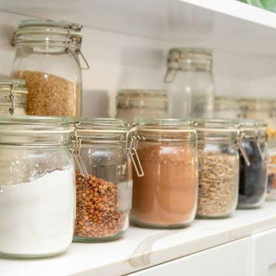 A collection of jars on a shelf, each full of a different colourful grain