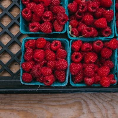 Pints of red raspberries in a black harvest crate