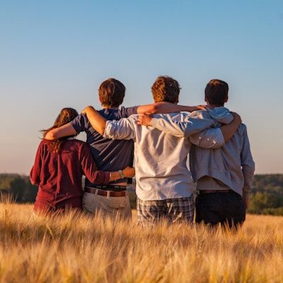 Group of people in a field with arms around each other